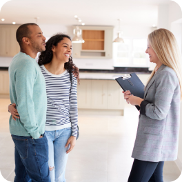 Una pareja sonríe al recibir el subsidio de vivienda nueva Colsubsidio con su asesora inmobiliaria.