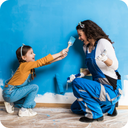 Madre e hija pintan un muro azul de su casa gracias al subsidio de mejoramiento vivienda Colsubsidio.