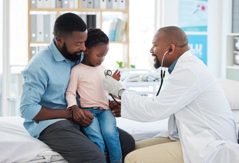 Médico revisa a una niña acompañada de su padre en consultorio médico