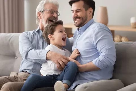 Padre, abuelo y nieto juegan en la sala de su vivienda Colsubsidio
