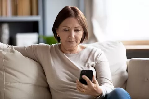 Mujer lee en el celular los requisitos para afiliarse