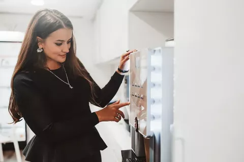 Mujer sacando café de maquina expendedora