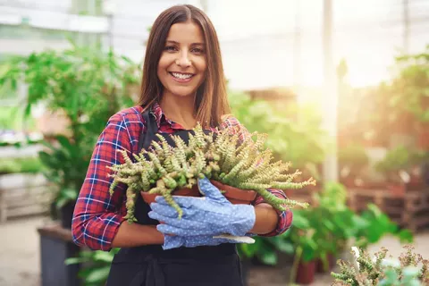 Mujer con una planta sonriendo
