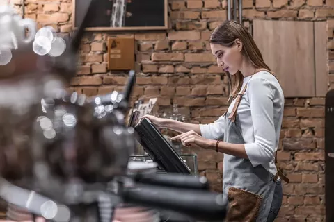 Trabajadora dependiente registra los pagos en su cafetería