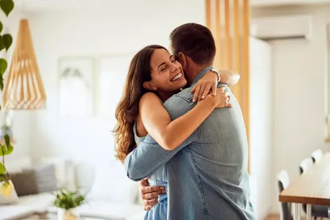 Pareja feliz se abraza en la sala de su vivienda Colsubsidio