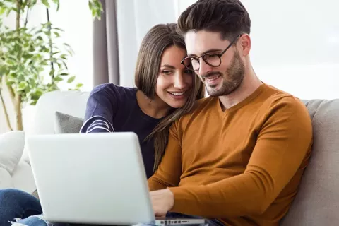 Pareja revisa su afiliación Colsubsidio desde portátil