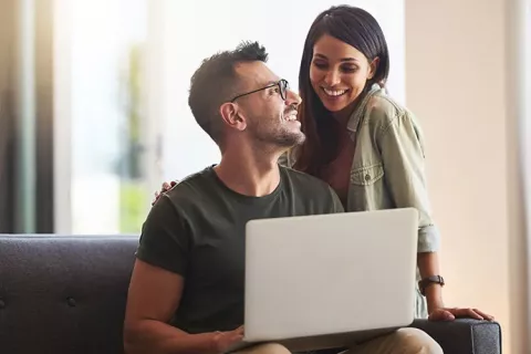 Pareja revisa su afiliación Colsubsidio desde portátil