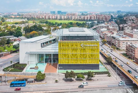 Vista aérea de la fachada del Club El Cubo Colsubsidio, rodeado de zonas verdes, vías y edificios.