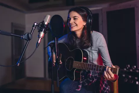 Mujer joven cantando con su guitarra en Teatro Colsubsidio