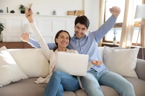 Hombre y mujer celebrando al frente de un computador