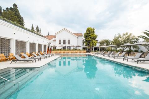 Piscina del Hotel Colonial Colsubsidio cuenta con sillas, arquitectura blanca y vegetación. 