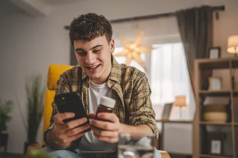 Hombre sostiene una medicina mientras ve el celular