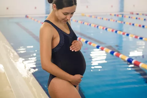 Madre en estado de gestación se prepara para ingresar a una piscina.