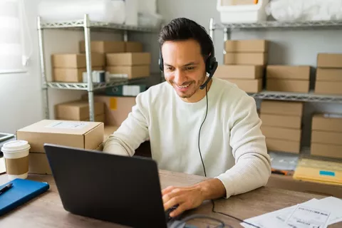 Hombre frente a computador portatil con audífonos de micrófono