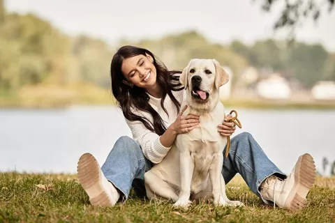 Mujer sentada en el pasto con su perro