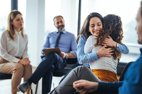 Asesora felicitando a afiliada por la entrega de vivienda propia.