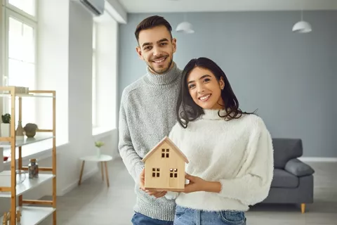 Pareja sosteniendo una maqueta de su casa.