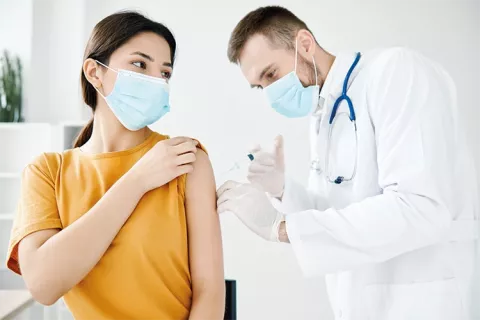 Médico vacuna a paciente en consultorio médico.