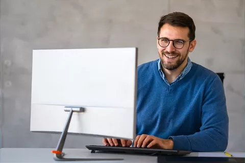 Hombre sonriente al frente de su computador.