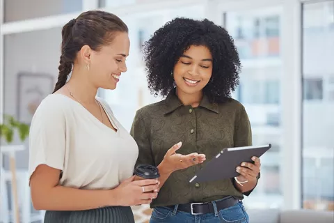 compañeras de trabajo revisando las ubicaciones de as escuelas deportivas Colsubsidio en su tablet.