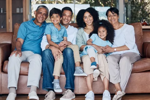Familia sentada en la sala de su casa y sonrientes.