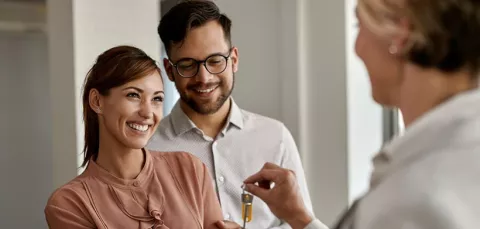 Pareja feliz recibiendo las llaves de su casa.