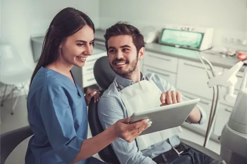 Odontóloga evalúa tratamiento dental con su paciente.