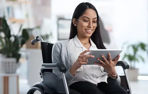 Mujer en silla de ruedas usando tablet.