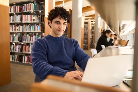 Estudiante realizando trabajos en la biblioteca.