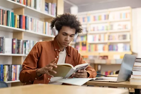 Joven estudiando en la biblioteca.