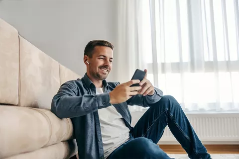 Hombre sonriente leyendo los beneficios de compra de cartera con Colsubsidio