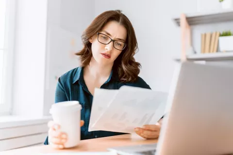 Mujer al frente de su portátil, estudiando sus apuntes sobre ahorro