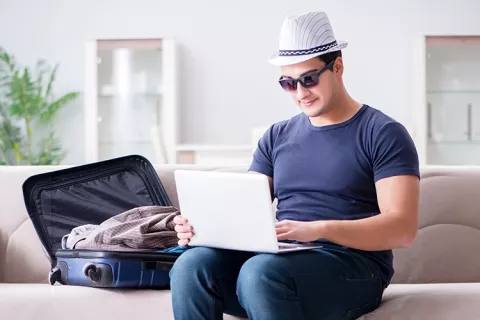 Señor en su portátil planeando las vacaciones con el crédito de libre inversión de Colsubsidio