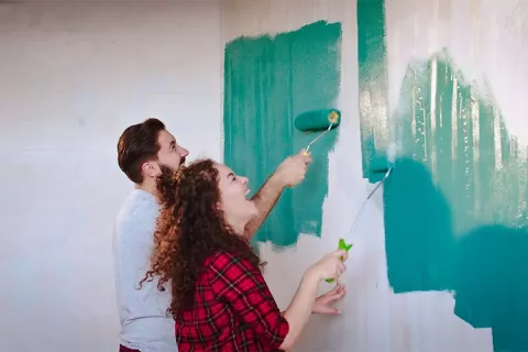 Pareja pintando las paredes de su vivienda