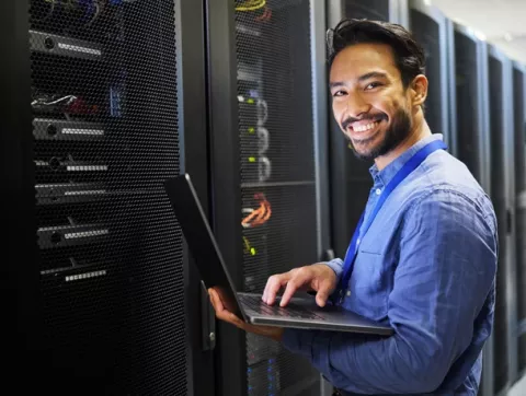 Joven sonriente actualizando los servidores de su empresa.