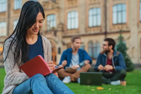 Estudiantes universitarios en las zonas verdes repasando apuntes
