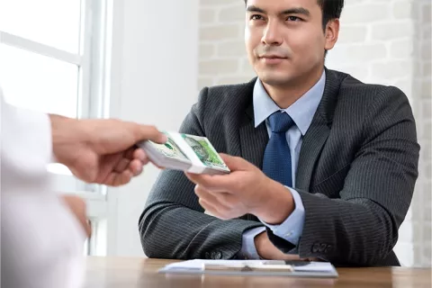 Hombre realizando pago de su crédito educativo en el banco