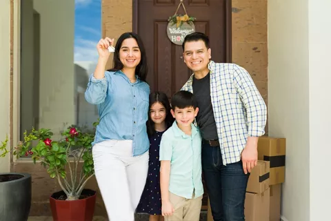 Una familia posa en la entrada de su nueva vivienda Colsubsidio, la madre enseña las llaves.