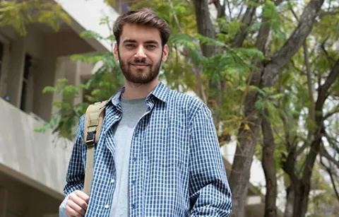 Joven feliz caminando por las zonas verdes de la ciudadela Maiporé.