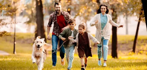 Familia corriendo por la zona campestre con su perro.