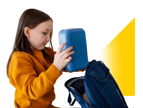 Niña empacando su lonchera en la maleta.