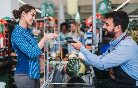 Mujer pagando una sandía en el supermercado aliado a Colsubsidio.