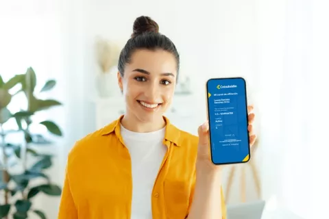 Mujer sonriente mostrando su carné de afiliación digital a Colsubsidio