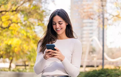 Mujer guardando su carné de afiliación a Colsubsidio en su celular.