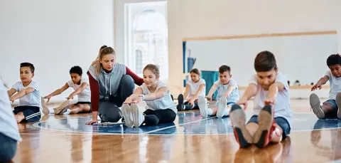 Niños y niñas realizando ejercicios de estiramiento en las escuelas deportivas de Colsubsidio.