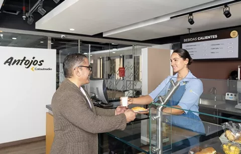 Hombre comprando una bebida caliente en la barra de café Antojos.