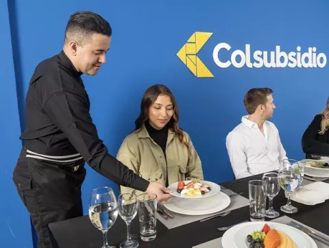 Mesero sirviendo plato fuerte en catering para empresas