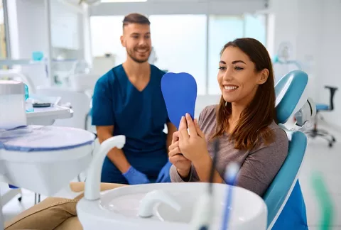 Mujer feliz mirando su sonrisa en espejo.