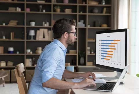Hombre al frente de su computador estudiando competencias productivas