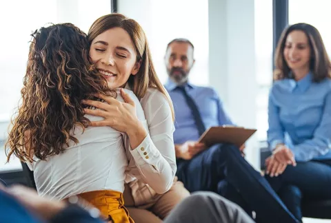 Mujer dando apoyo abrazo a otra en una reunión